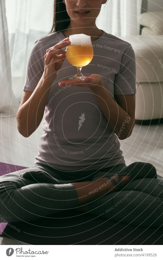 Crop-Frau in Lotus-Pose mit einem Glas Bier Yoga trinken Alkohol padmasana üben Asana heimwärts Unterlage Wohlbefinden Getränk sitzen Vitalität Harmonie