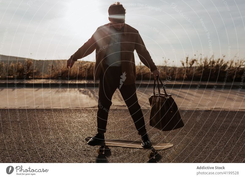 Junger bärtiger Skater mit Tasche fährt auf der Straße Mann Longboard Fähigkeit Mode Stil Skateboard Asphalt Mitfahrgelegenheit Hobby Aktivität männlich