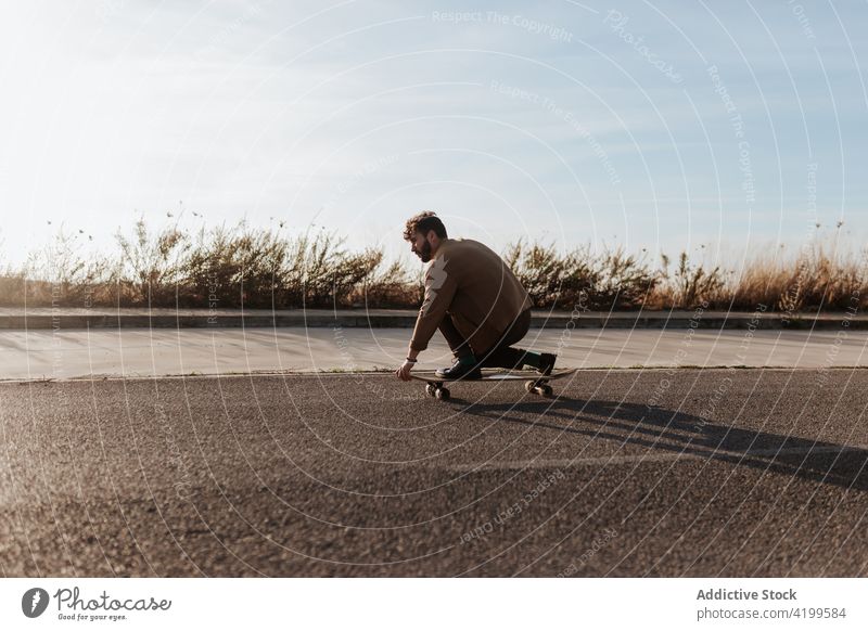 Trendiger Skater, der auf einer Landstraße einen Trick vorführt Mann ausführen Straße Landschaft Natur ländlich Asphalt berühren Boden Fähigkeit Talent männlich