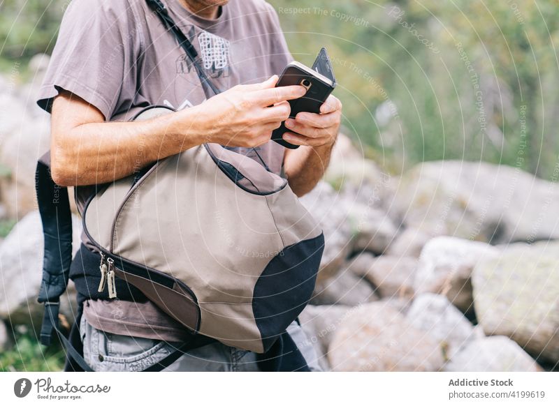 Crop Backpacker auf dem Mobiltelefon Trekker Smartphone Bildschirm Urlaub erkunden Mann benutzend Apparatur Gerät Ausflug Fernweh Wanderung Funktelefon