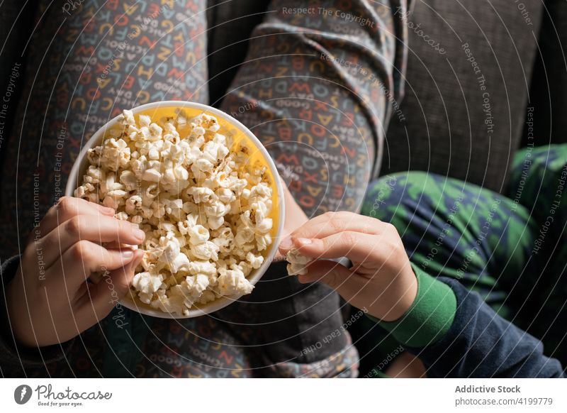Anonyme Geschwister auf der Couch, die fernsehen und Popcorn essen Zusammensein genießen Filmmaterial Liege Spaß haben Cartoons Kinder Lifestyle Sofa Snack