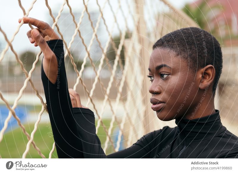 Melancholische schwarze Frau am Gitterzaun in der Stadt Kurze Haare Melancholie wehmütig reflektierend feminin Einsamkeit sanft Zaun urban Porträt Stil