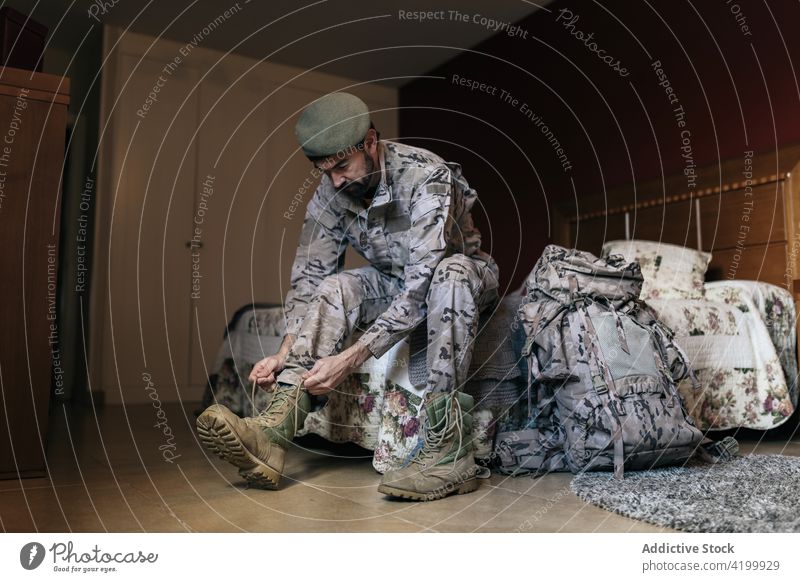 Seriöser Mann beim Schnüren von Stiefeletten Soldat Militär Spitze befestigen Dienst Armee Tarnung Verteidigung Munition männlich behüten angezogen Krieger