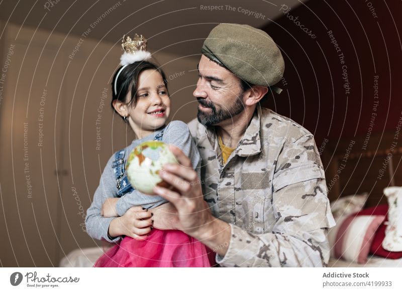 Lächelnder Vater, der auf einen Ort auf dem Globus zeigt Tochter Soldat erklären Punkt Armee Verteidigung dienen Militär Mädchen Mann Papa sprechen wehren
