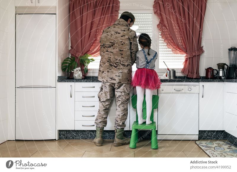 Militärischer Mann am Tresen stehend mit Tochter in der Küche Vater Zusammensein Soldat heimwärts Waschen Abfertigungsschalter Heimkehr ankommen Liebe Kind