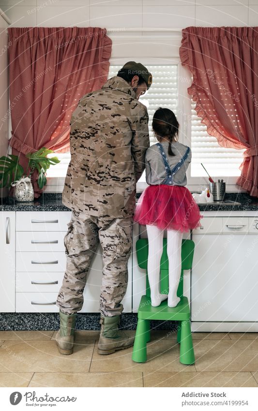 Militärischer Mann am Tresen stehend mit Tochter in der Küche Vater Zusammensein Soldat heimwärts Waschen Abfertigungsschalter Heimkehr ankommen Liebe Kind