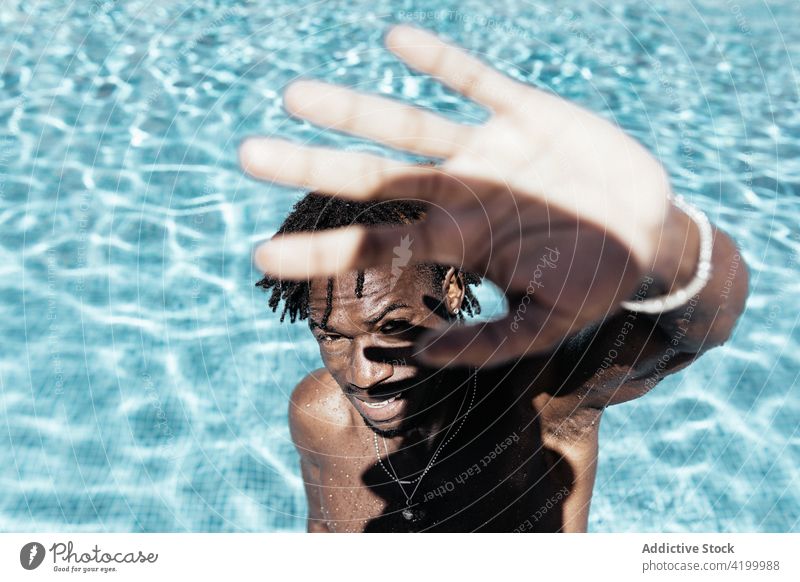 Schwarzer Mann schützt sein Gesicht im Schwimmbad vor der Sonne Pool Sommer Wasser Deckblatt sonnig Urlaub nackter Torso Feiertag Sonnenlicht männlich ethnisch