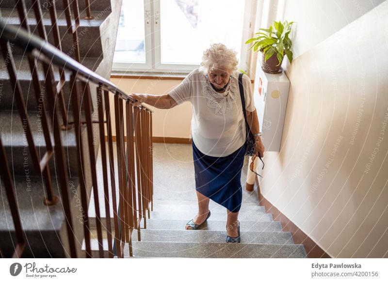 Ältere Frau steigt mühsam eine Treppe hinauf Menschen Senior reif lässig Kaukasier älter heimwärts Haus alt Alterung häusliches Leben Großmutter Rentnerin