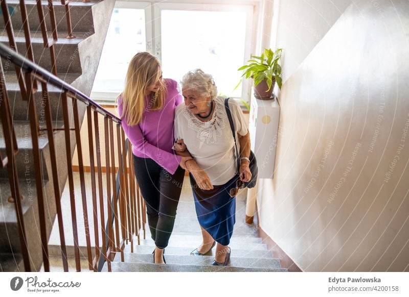 Pflegerin hilft Seniorin beim Treppensteigen Menschen Frau reif lässig Kaukasier älter heimwärts Haus alt Alterung häusliches Leben Großmutter Rentnerin
