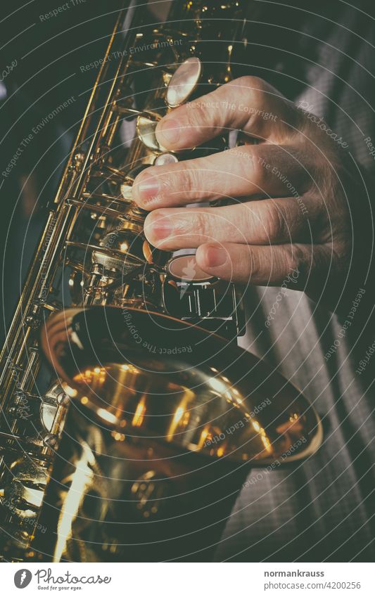 Saxofon und Musiker saxophon hand finger musikinstrument blasinstrument musiker glanz gold messing holzblasinstrument musikant