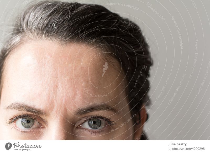 Vierzigjährige Frau blickt in die Kamera; natürliches graues Haar wächst ein Behaarung Haarpflege wachsen auswachsen Farbstoff farbstofffrei Quarantäne Silber