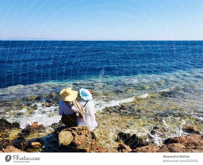 Zwei Frauen mit Sonnenhut sitzen am Meer Sommer sommerlich Sommerurlaub Sommertag Sommerkleid blau Blauer Himmel blau-weiß Ägypten Afrika