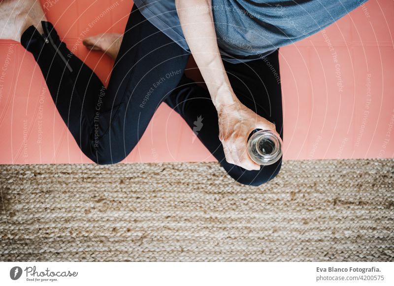 Draufsicht auf reife kaukasische ältere Frau übt Yoga-Pose zu Hause. Sie hält eine Flasche Wasser. Gesunder Lebensstil trinken Senior heimwärts Sport Gesundheit