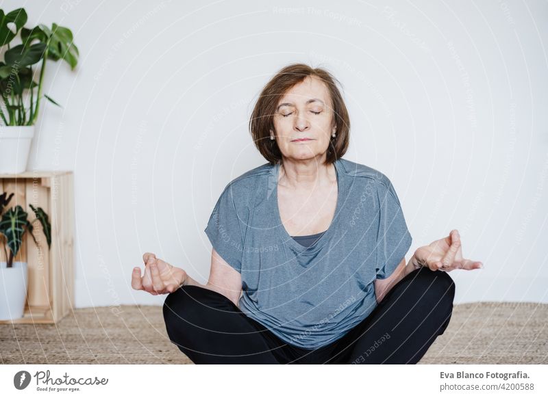 reife kaukasische ältere Frau übt Yoga zu Hause auf Yogamatte. Gesunder Lebensstil Senior heimwärts Sport Gesundheit Kaukasier Stock alt aktiv Rentnerin
