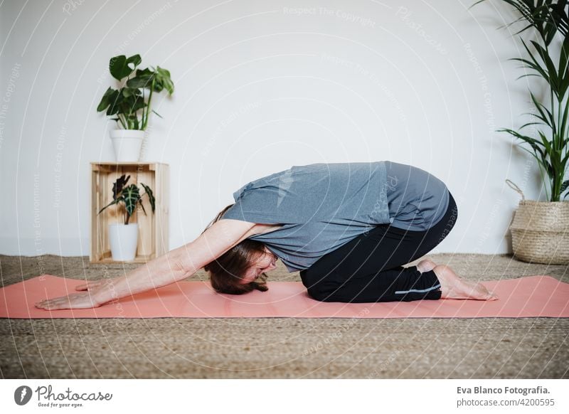 Draufsicht auf reife kaukasische Seniorin, die zu Hause auf der Yogamatte Yoga übt. Gesunder Lebensstil Frau heimwärts Sport Gesundheit Kaukasier Stock alt