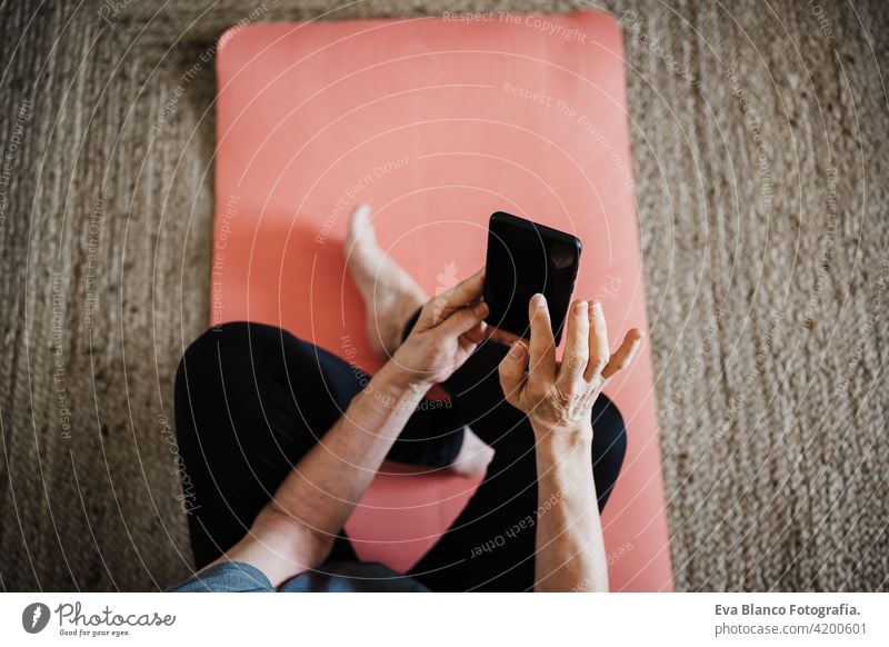 reifen kaukasischen Senior Frau übt Yoga-Pose zu Hause. mit Handy. Technologie und gesunder Lebensstil Technik & Technologie Internet online Drahtlos heimwärts