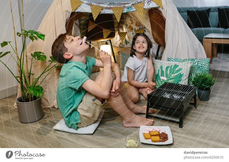 Brüder haben Spaß beim Essen von Marshmallows staycation Camping zu Hause Spaß haben Diy-Zelt Röstung Barbecue sich zum Narren machen Lager Urlaub zu Hause heiß