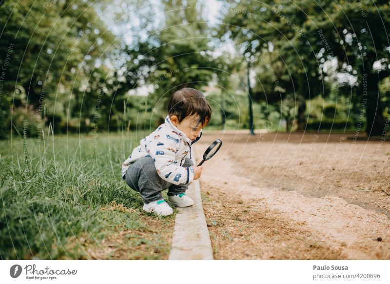 Kind spielt mit Lupe 1-3 Jahre Kaukasier Neugier Natur Junge Außenaufnahme Spielen Mensch Kleinkind Freude Farbfoto Kindheit authentisch erkunden mehrfarbig