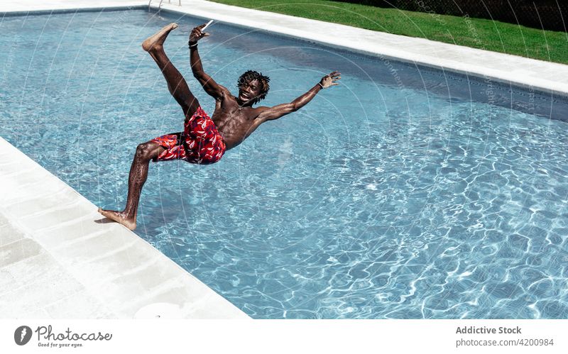 Schwarzer Mann mit Smartphone fällt in Pool fallen Erstaunen ausrutschen Schock erstaunt Browsen Beckenrand männlich ethnisch schwarz Afroamerikaner Mobile