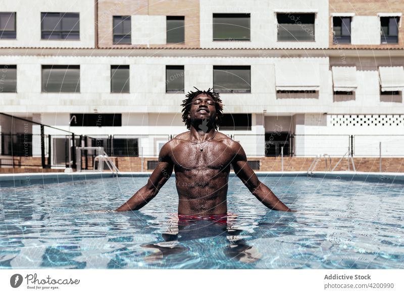 Schwarzer Mann im Schwimmbad Pool Sommer Urlaub genießen Wasser nackter Torso sorgenfrei sonnig Shorts männlich ethnisch schwarz Afroamerikaner Feiertag Freude