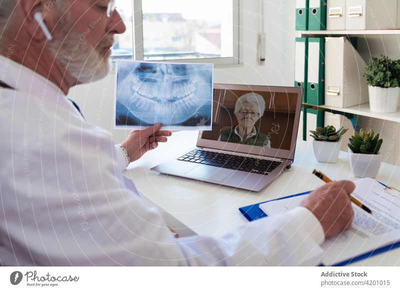 Arzt im Gespräch mit dem Patienten per Videochat auf dem Laptop geduldig Videoanruf abgelegen Beratung online Bildschirm Mann benutzend Apparatur Ohrstöpsel
