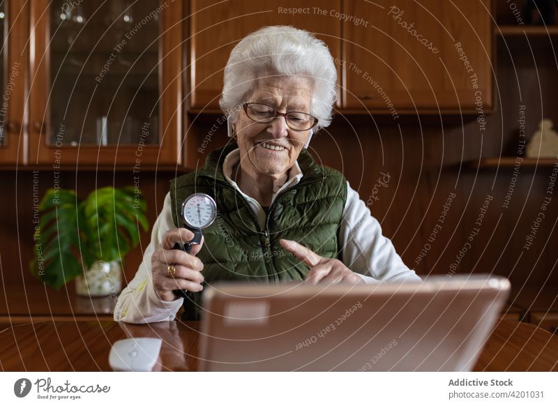 Älterer Patient mit Druckmessgerät während eines Videochats auf einem Tablet geduldig Tablette Videoanruf Sphygmomanometer Lächeln zeigen Blut Frau benutzend