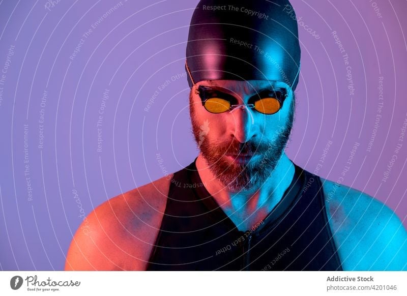 Porträt eines Schwimmers mit Kappe und Schwimmbrille, der nach unten schaut Atelier Mann Hintergrund Verschlussdeckel Brille bärtig Gesundheit Gesicht jung