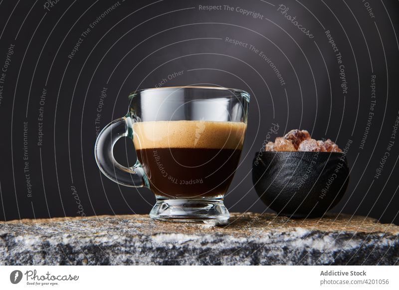Glas Espresso neben Rohrzucker auf Steinoberfläche Kaffee Zucker Heißgetränk Aroma süß Getränk schäumen kreativ Design lecker Würfel braun Schalen & Schüsseln
