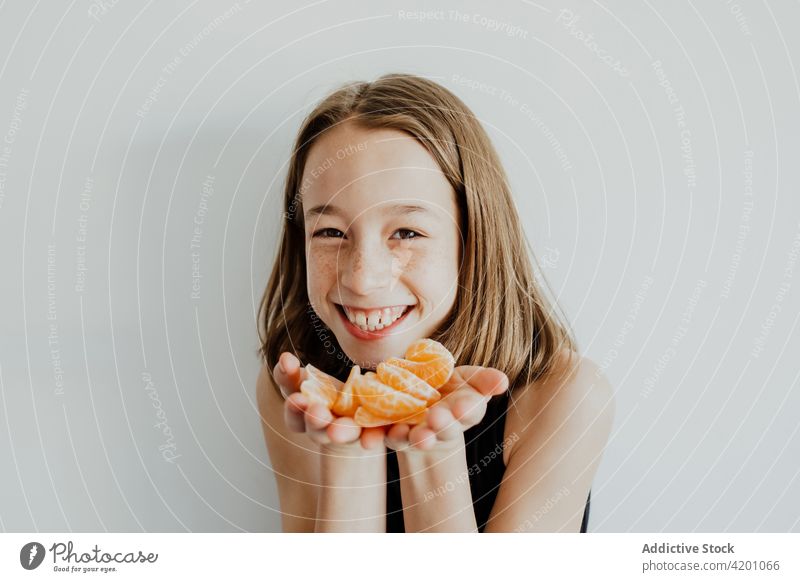 Fröhliches Mädchen zeigt Mandarinenscheiben und lächelt in die Kamera manifestieren Scheibe Lächeln positiv Porträt Frucht Vitamin gesunde Ernährung froh heiter