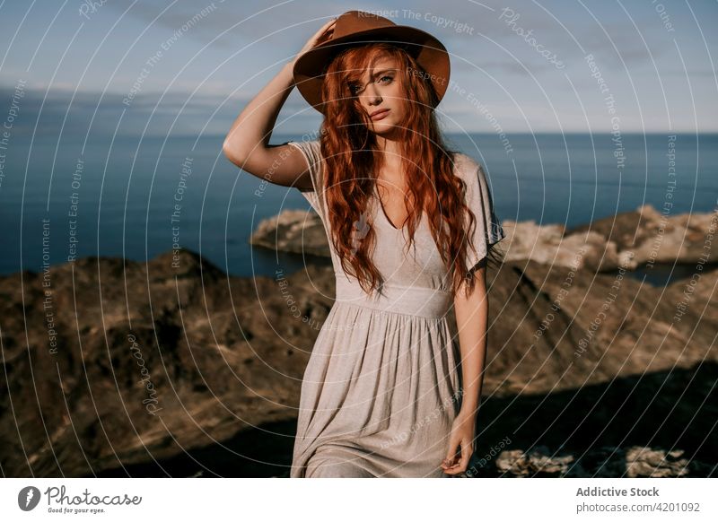 Rothaarige Frau entspannt sich in den Bergen am Meer rote Haare Felsen hoch Top Rotschopf Natur Küste Stehen Berge u. Gebirge Wildnis Freiheit reisen natürlich