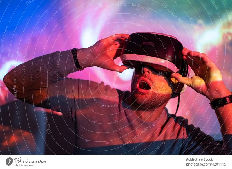 Mann mit VR-Brille erkundet virtuelle Realität Virtuelle Realität Headset Schutzbrille berühren Erfahrung erkunden leuchten Projektor Technik & Technologie