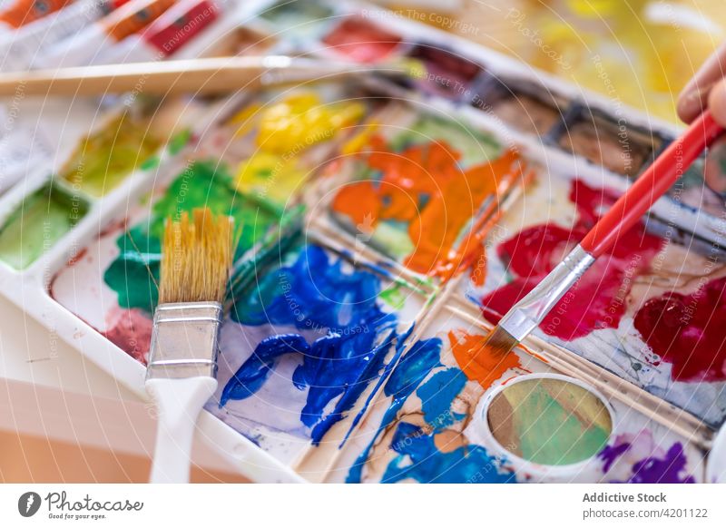 Aquarellmaler beim Mischen von Aquarellfarben mit Pinsel im Arbeitszimmer Anstreicher mischen Farbe Palette Pinselblume Wasserfarbe Kunst professionell