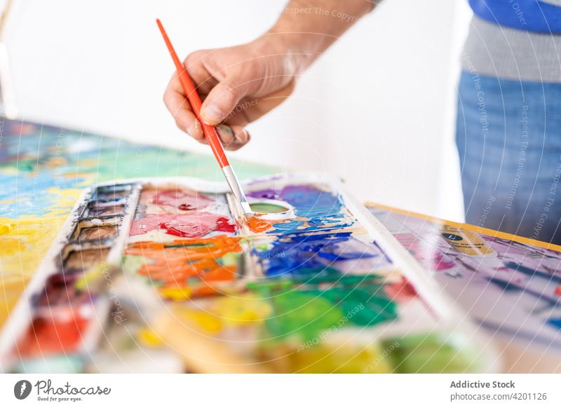 Aquarellmaler beim Mischen von Aquarellfarben mit Pinsel im Arbeitszimmer Anstreicher mischen Farbe Palette Pinselblume Wasserfarbe Kunst professionell Mann