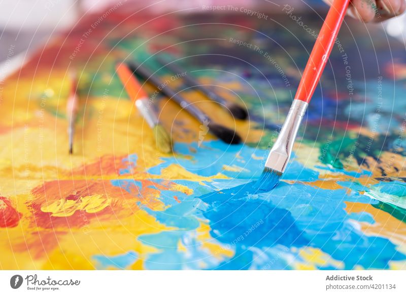 Crop Artist malt mit Pinsel auf Karton in der Werkstatt Anstreicher Farbe Kunst Pinselblume Fähigkeit Talent Werkzeug Mann Arbeitsraum Wasserfarbe professionell