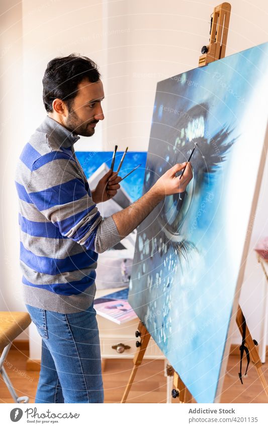 Hispanischer männlicher Künstler malt ein Bild in einem Workshop Farbe Leinwand Kunstwerk kreativ Design Talent professionell Mann Werkstatt Bürste Anstreicher