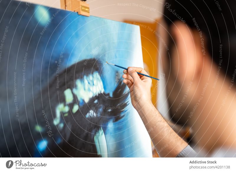 Anonymer männlicher Künstler malt ein Bild in einer Werkstatt Farbe Leinwand Kunstwerk kreativ Design Talent professionell Mann Bürste Anstreicher hispanisch