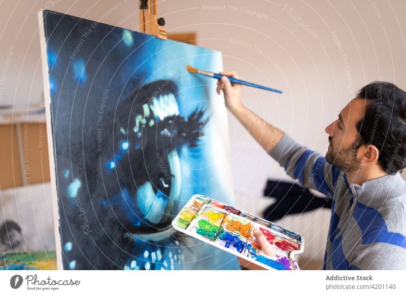 Hispanischer männlicher Künstler malt ein Bild in einem Workshop Farbe Leinwand Kunstwerk kreativ Design Talent professionell Mann Werkstatt Bürste Anstreicher