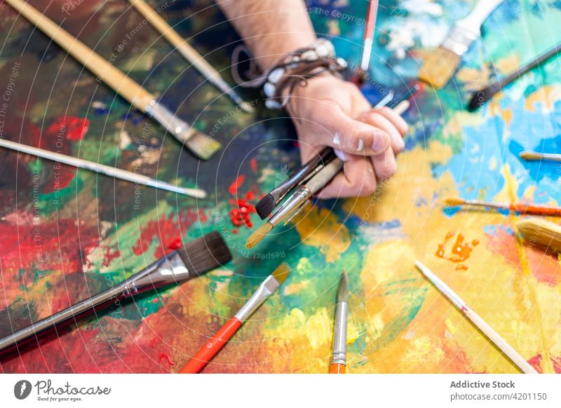 Crop Artist mit verschiedenen Pinseln auf buntem Gemälde Künstler Pinselblume Malerei Kunst Talent Fähigkeit professionell Mann Sammlung farbenfroh anders