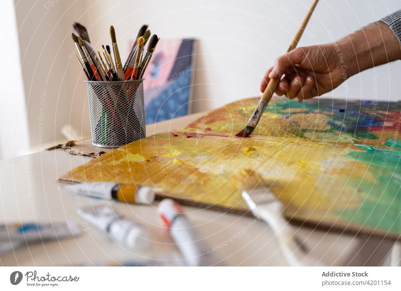 Crop Artist malt mit Pinsel auf Karton in der Werkstatt Anstreicher Farbe Kunst Pinselblume Fähigkeit Talent Werkzeug Mann Arbeitsraum Wasserfarbe professionell