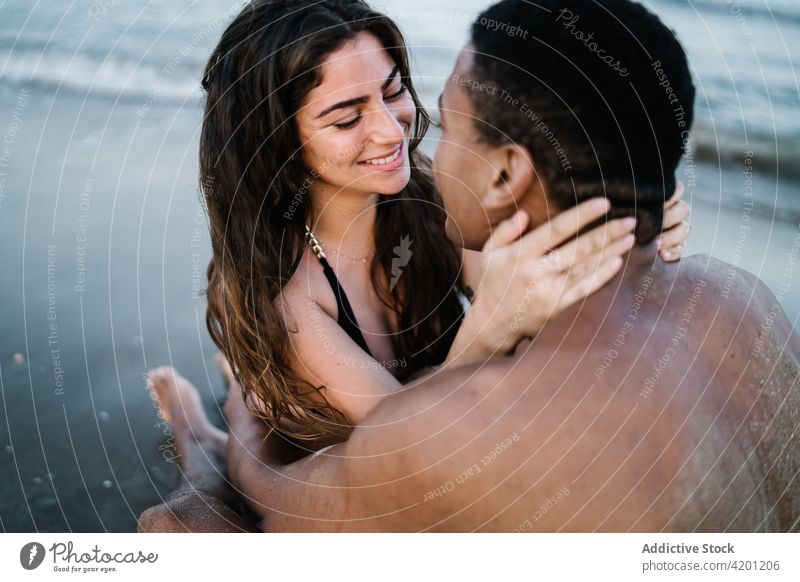 Lächelndes multiethnisches Paar von Reisenden, die sich am Meeresufer umarmen Umarmen Liebe Partnerschaft Flitterwochen Romantik Vergnügen Urlaub ruhen