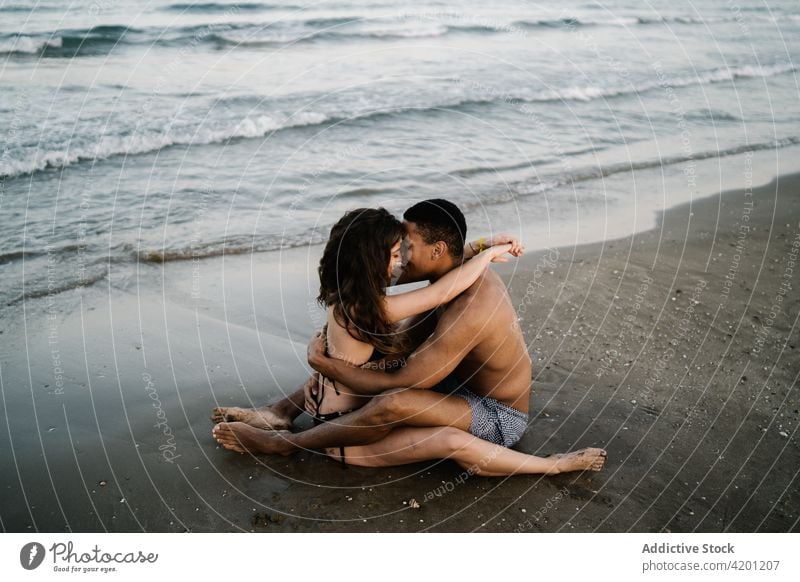 Lächelndes multiethnisches Paar von Reisenden, die sich am Meeresufer umarmen Umarmen Liebe Partnerschaft Flitterwochen Romantik Vergnügen Urlaub ruhen