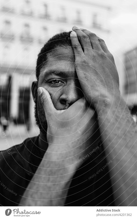 Anonymer afroamerikanischer Demonstrant, der sein Gesicht auf einer Straße der Stadt verdeckt Protestierender Deckel Mund Auge abdecken BLM Bewegung rassisch