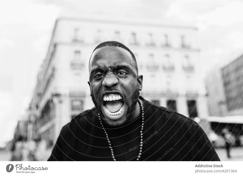 Aggressiver schwarzer Demonstrant schreit auf einer Straße in der Stadt Protestierender Schrei angriffslustig wütend BLM auflehnen Mann Porträt verärgert