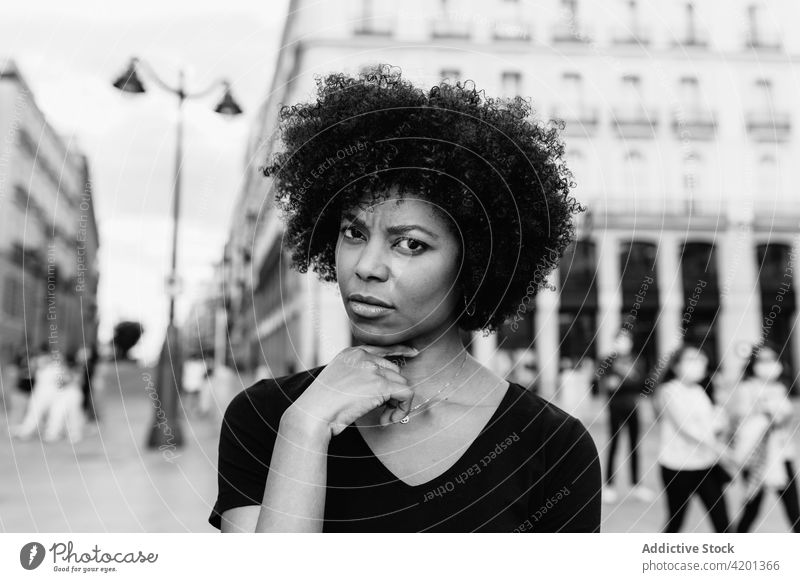 Nachdenkliche schwarze Frau auf städtischem Bürgersteig bei Tag Afro-Look Frisur Straße Großstadt Porträt Afroamerikaner urban ethnisch Quadrat Stadt