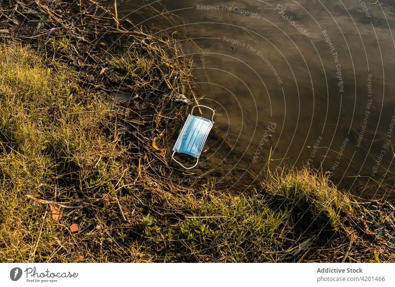 Benutzte medizinische Maske im Wasser des Sees Mundschutz verschmutzen Umwelt Müll verwendet Konzept dreckig Abfall behüten Teich Trümmer Natur Ökologie Erde