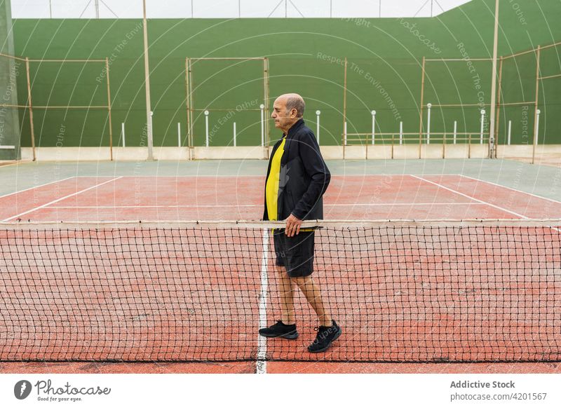 Senior-Tennisspieler in der Nähe des Netzes Sportler Gericht Ball Training Aktivität Spiel Streichholz männlich älter gealtert schäbig verwittert Athlet