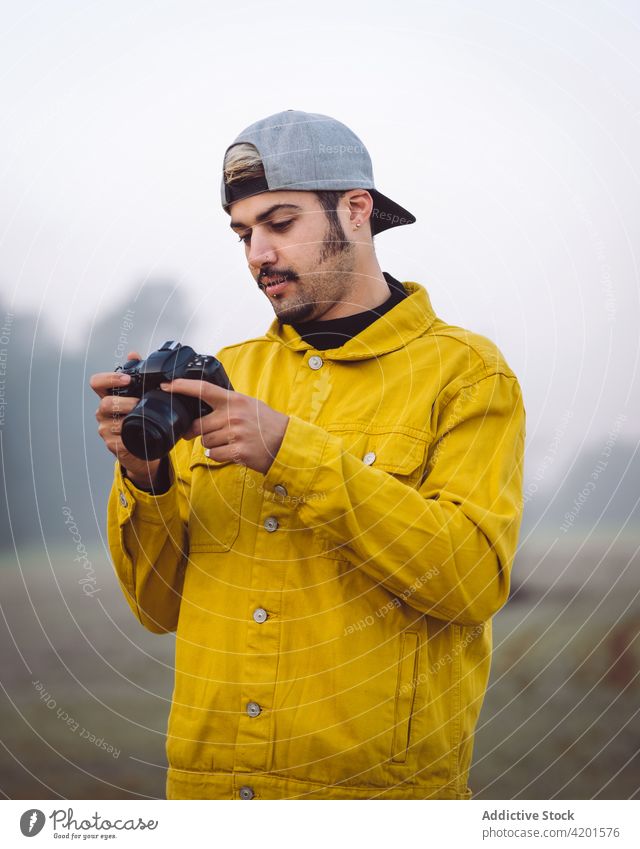 Mann nimmt Foto auf Kamera in nebliger Natur fotografieren Landschaft Nebel Fotografie Fotoapparat Wiese Jeansstoff Lifestyle Gerät Apparatur jung Mobile
