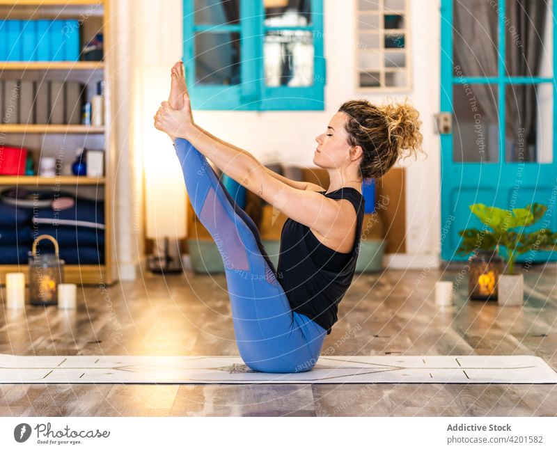 Ruhige Frau macht Yoga in Navasana Übung Dehnung Pose Aktivität Wohlbefinden Boot-Pose Konzentration Asana navasana üben Sportkleidung Atelier Zen Achtsamkeit