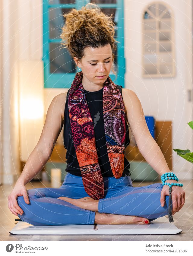 Frau meditiert während einer Yoga-Praxis Asana üben halber Lotus Zen Achtsamkeit Sportkleidung Unterlage Wohlbefinden Atelier Wellness friedlich meditieren
