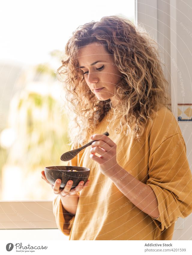 Ruhige Frau beim gesunden Frühstück in der Wohnung Windstille besinnlich essen Lebensmittel Gesundheit nachdenklich Raum Schalen & Schüsseln krause Haare ruhig